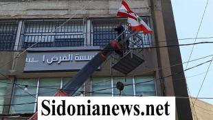 بالفيديو والصور  :إقفال فرع القرض الحسن في صيدا وفرق بلدية صيدا أزالت لافتة الجمعية من واجهة المبنى ورفعت الأعلام اللبنانية مكانها